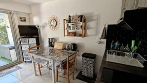 Een moderne keuken met een marmeren aanrecht, houten stoelen, een koffieapparaat en een zwart fornuis.