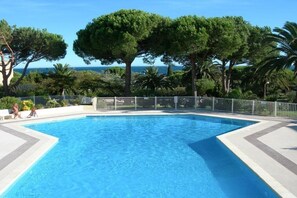 A swimming pool with a view of the sea, surrounded by trees and a white fence. - JARDINS D'YS Studio for 2 people with air conditioning (LES ISSAMBRES)