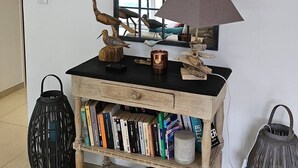 Ein Zimmer mit einem Holzkonsolentisch, Büchern, dekorativen Gegenständen und einem großen Spiegel mit schwarzem Rahmen.