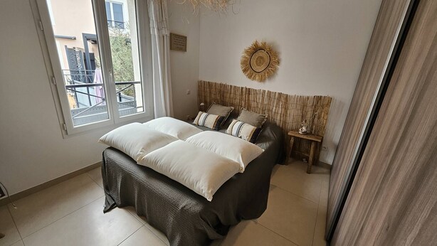 Ein Schlafzimmer mit einem Bett, einem Fenster, einer Wanddekoration und einem kleinen Holztisch.