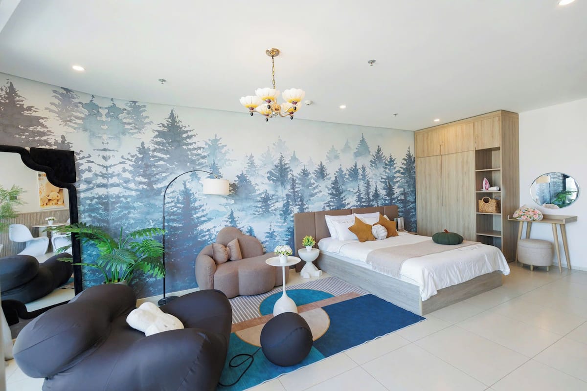 Un dormitorio moderno con cama, zona de estar y un mural de un bosque.