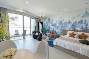 Une chambre moderne avec un grand lit, un canapé, une table à manger et un balcon équipé de chaises.