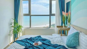 Ein Schlafzimmer mit großem Fenster, einem Bett, einem Nachttisch und Meerblick.