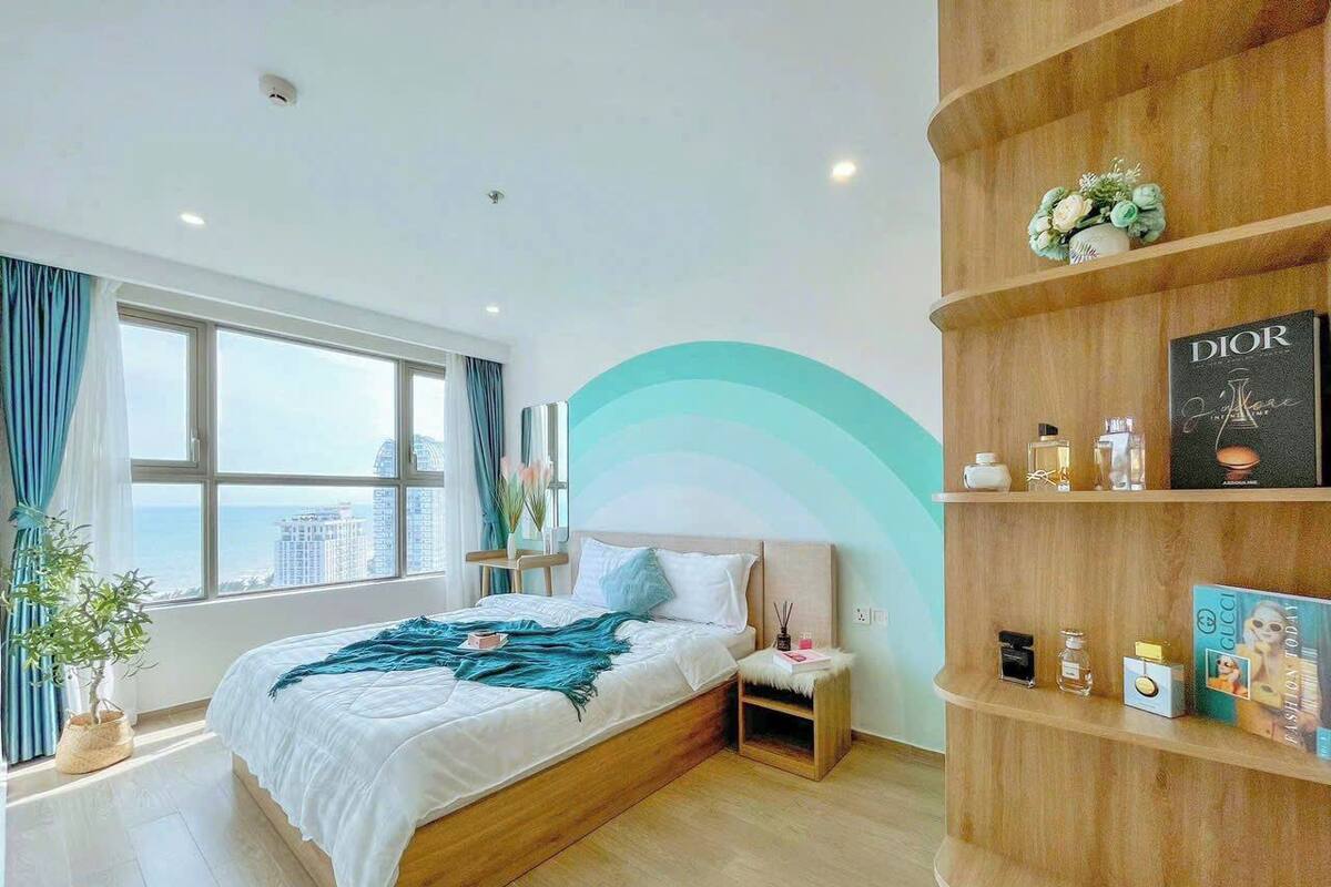 Un dormitorio con cama, mesita de noche y estante de madera con objetos.