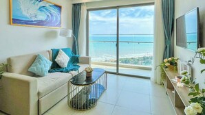 Ein modernes Wohnzimmer mit einer Couch, einem Couchtisch und einem großen Fenster mit Blick aufs Meer.