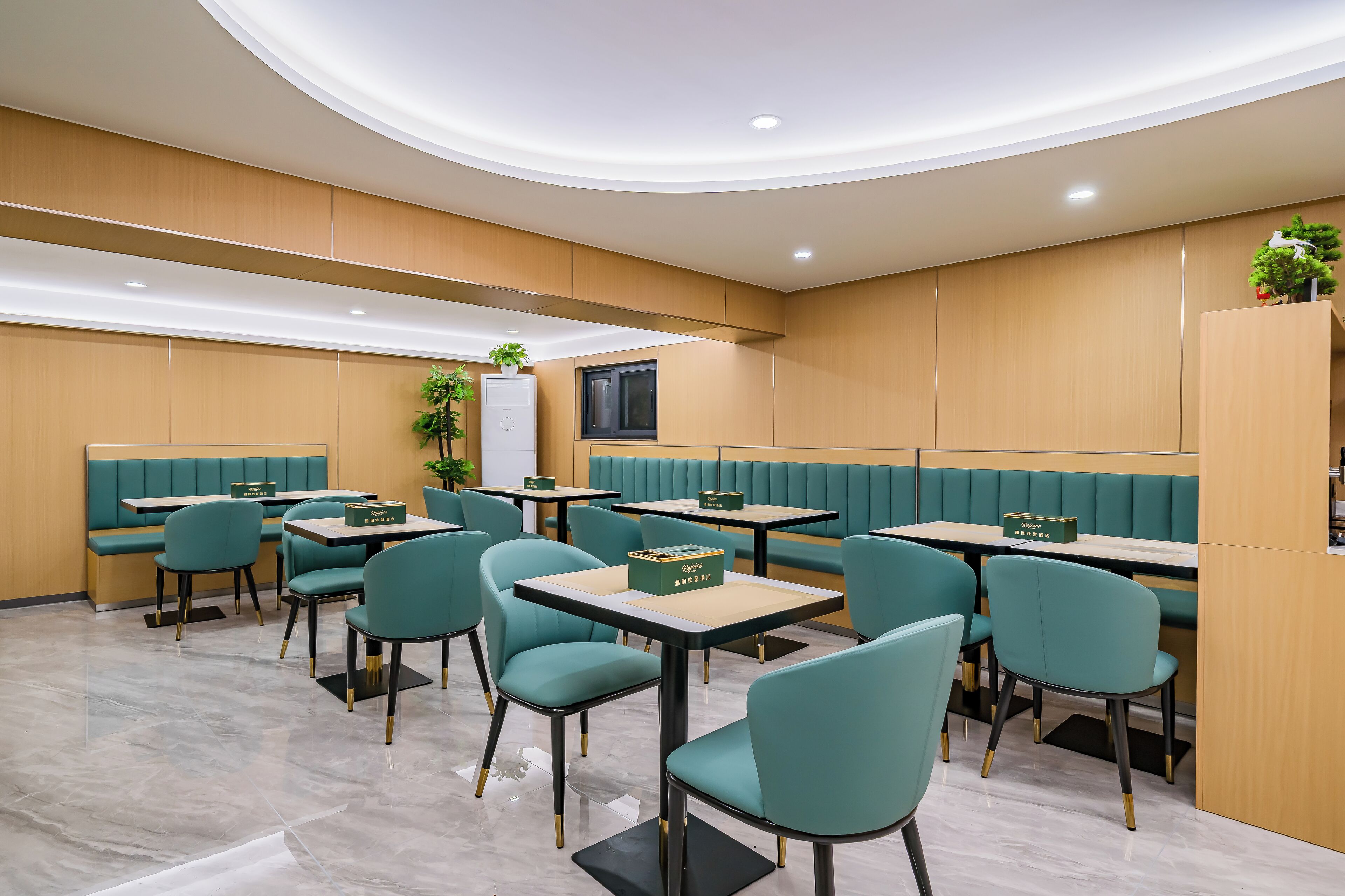 A modern restaurant with teal chairs and tables, wooden panel walls, and recessed ceiling lighting.