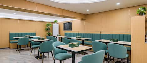 A modern restaurant with teal chairs and tables, wooden panel walls, and recessed ceiling lighting.