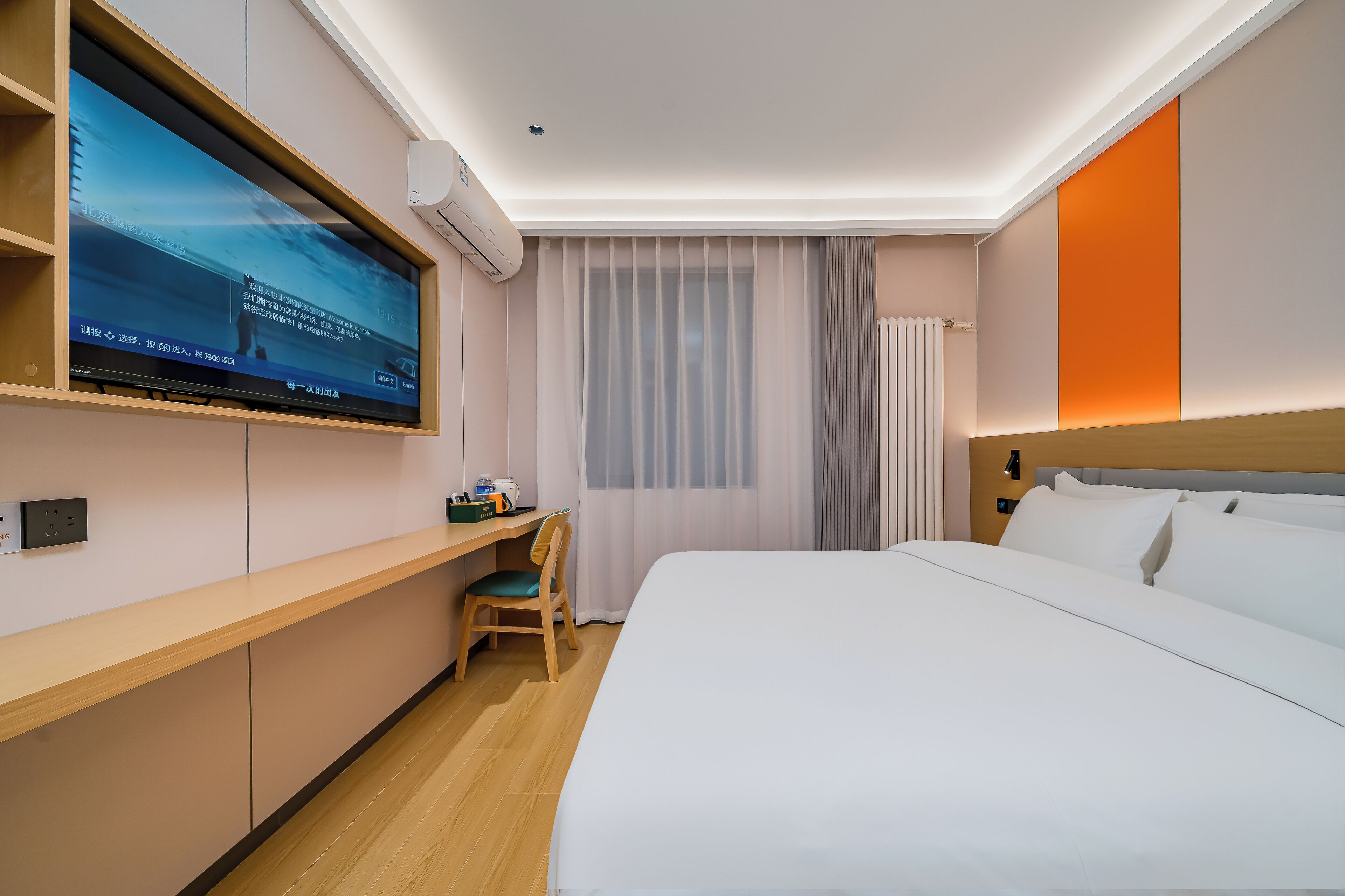 Een hotelkamer met een bed, een bureau met stoel, een televisietoestel en een raam met gordijnen.