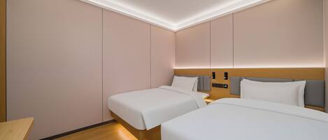 Een hotelkamer met twee bedden, houten vloeren en een modern plafondontwerp.