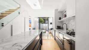 Eine moderne Küche mit Marmorarbeitsplatte, Edelstahlgeräten und Holzboden.