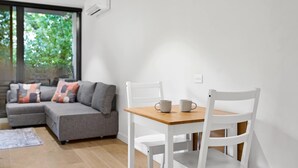 En moderne stue med en grå sofa, hvide stole og et træbord.