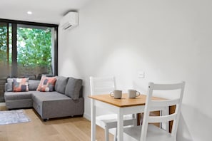 Ein modernes Wohnzimmer mit einem grauen Sofa, weißen Sesseln und einem Holztisch.