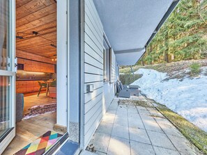 Ein modernes Haus mit Holzinneneinrichtung, einer überdachten Terrasse und einer verschneiten Umgebung.