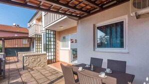 Un patio al aire libre con una mesa y sillas, un muro de piedra y vistas a un edificio con balcón.