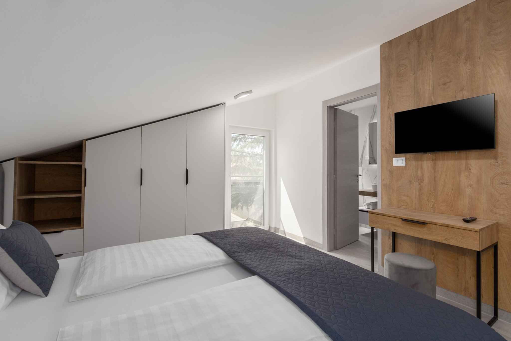 A modern bedroom with a bed, a desk, and a TV.