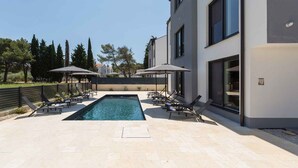 A modern building with a swimming pool, sun loungers, and umbrellas. - Holiday apartment with shared pool (Funtana)