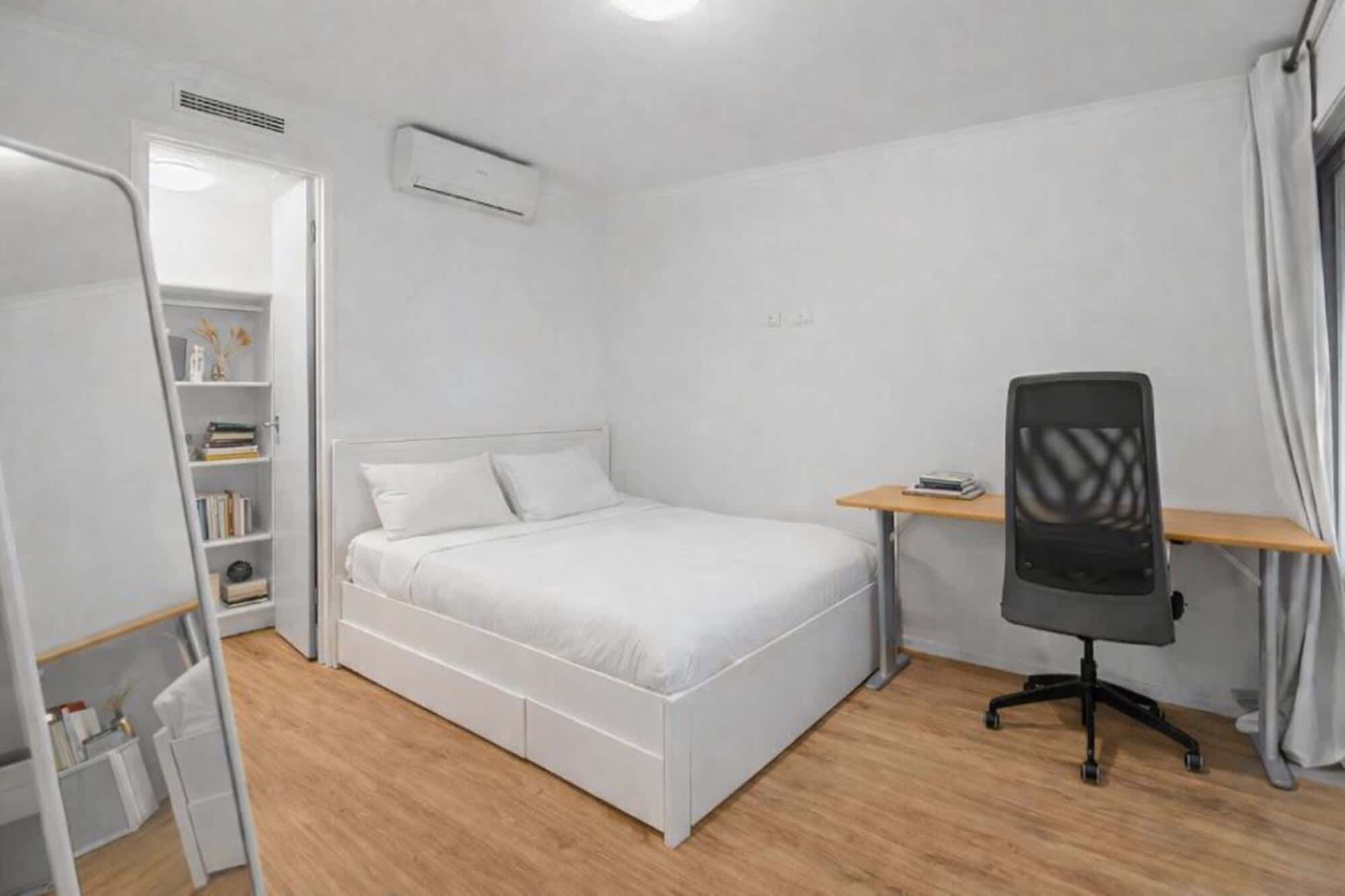 Un dormitorio con cama, escritorio y silla.