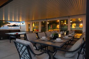 An outdoor dining area with tables and chairs, a pool, and a view of the sunset. - Vegas Stays with Games, Volleyball, and More! (North Las Vegas)