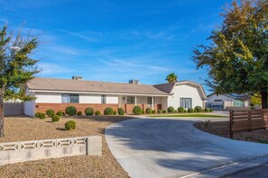 A two-story house with a driveway, a small garden, and a tree. - Vegas Stays with Games, Volleyball, and More! (North Las Vegas)