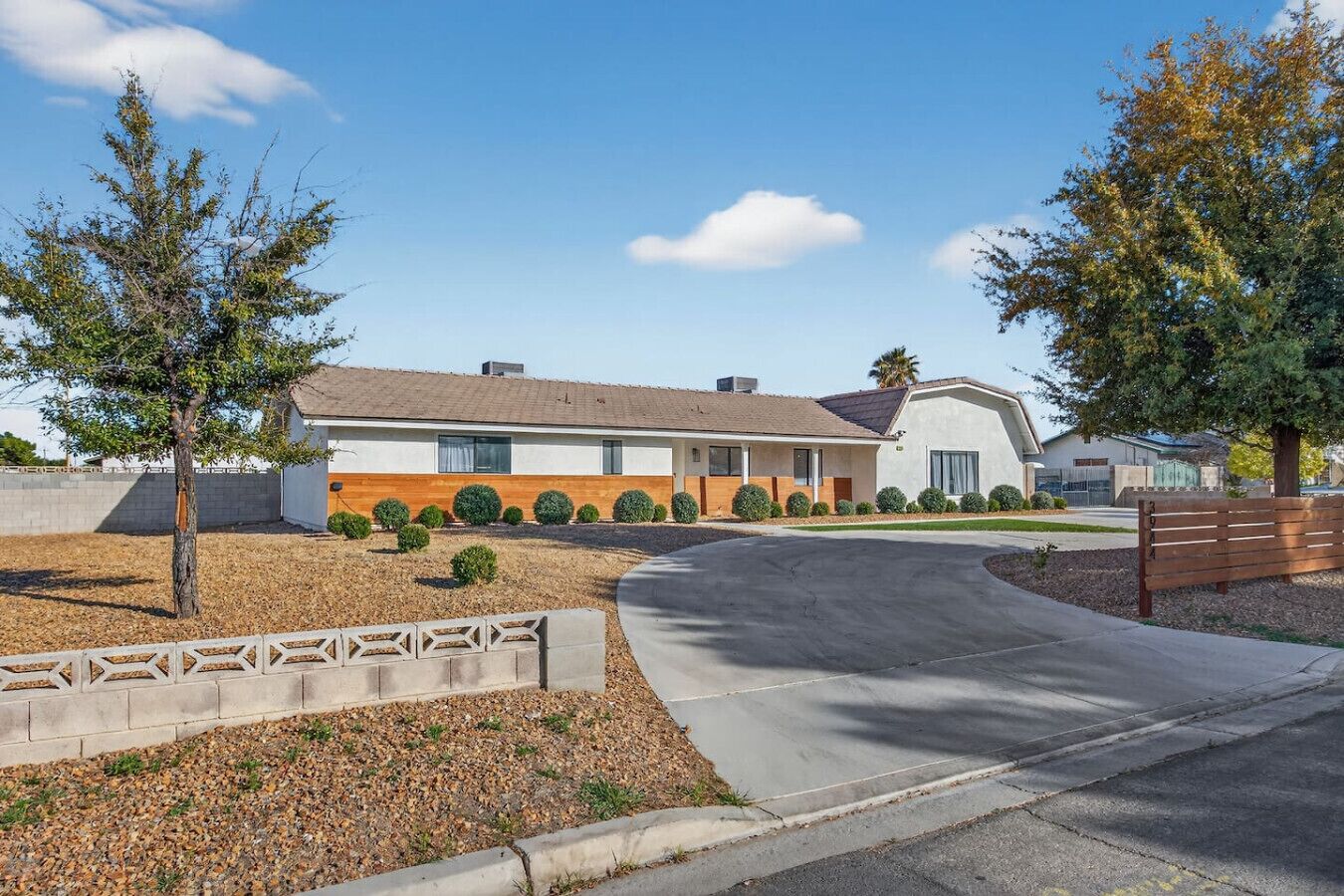 A modern two-story house with a driveway, a small garden, and a wooden fence.