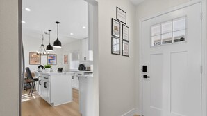 Une cuisine moderne avec des meubles blancs, des luminaires suspendus et un petit îlot central.