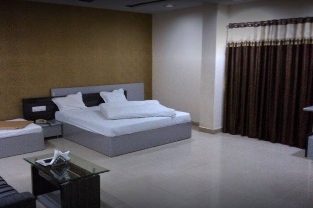 A hotel room with a bed, a nightstand, a glass table, and a sofa.