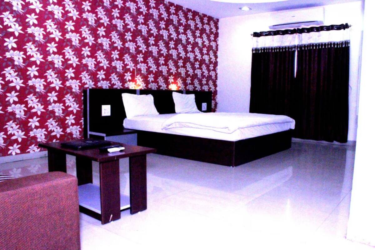 A bedroom with a large bed, a bedside table, and a chair.