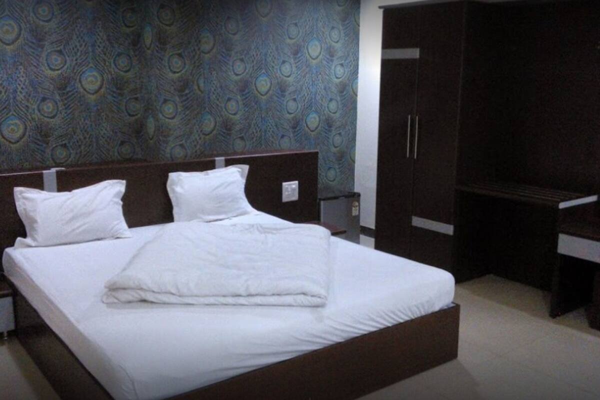 A hotel room with a large bed, a wardrobe, and a desk.