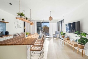 Una cucina moderna con un'isola in legno, sgabelli da bar, piante pensili e un'ampia finestra.