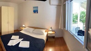 A bedroom with a bed, a wardrobe, a television, a window with a view, and a small painting on the wall. - Holiday Apartment Mandarin (Sv. Filip i Jakov)