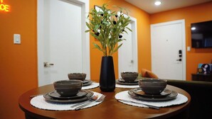 A dining table set with bowls and plates, a vase with greenery, and a neon sign in the background. - The Tangerine Retreat - Retro Dallas Downtown Vibe (Dallas)