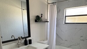 Une salle de bain avec un grand miroir, deux lavabos, des toilettes et une baignoire.