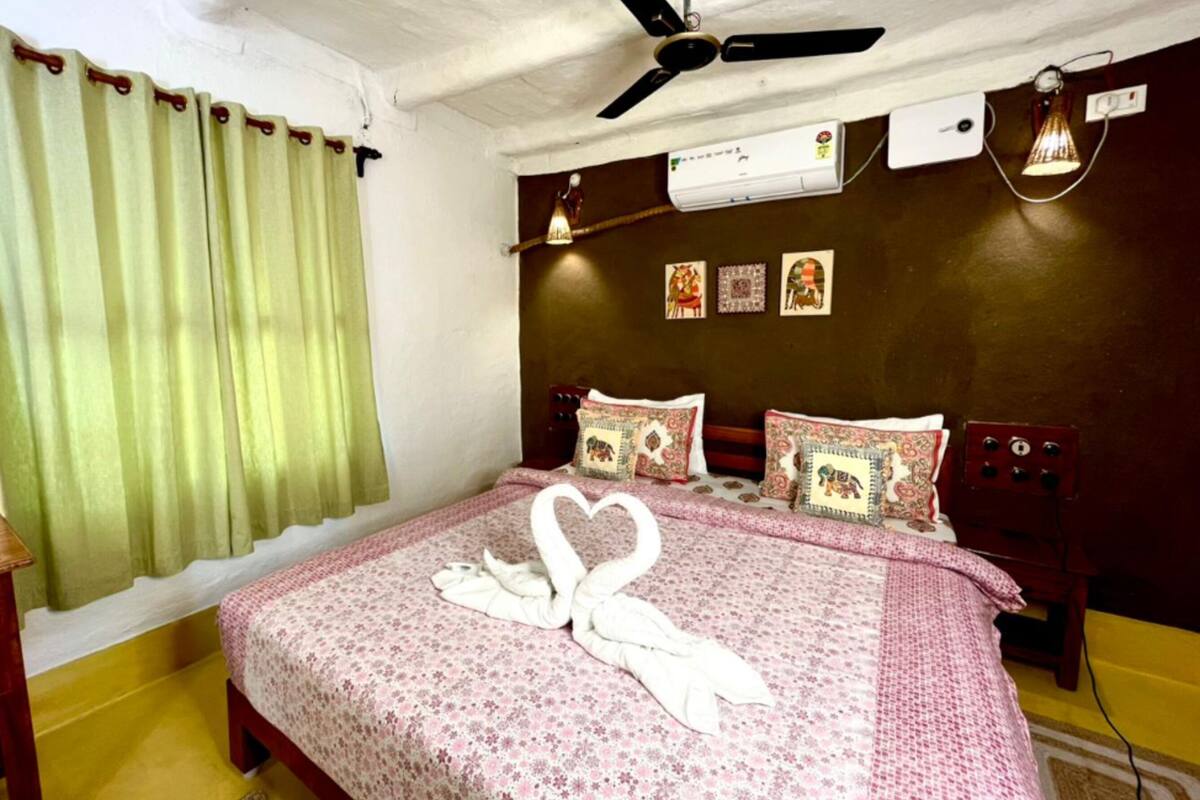 Une chambre à coucher comprenant un lit, un ventilateur de plafond, un climatiseur et un mur décoré.