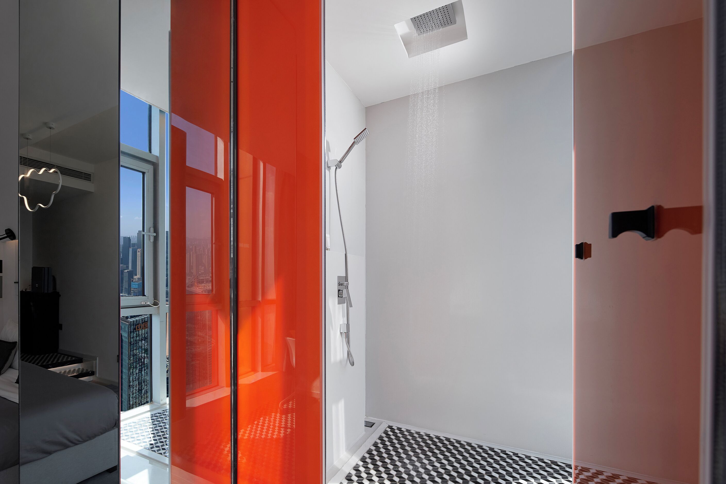 Un baño moderno con ducha, mampara de vidrio y piso a cuadros.