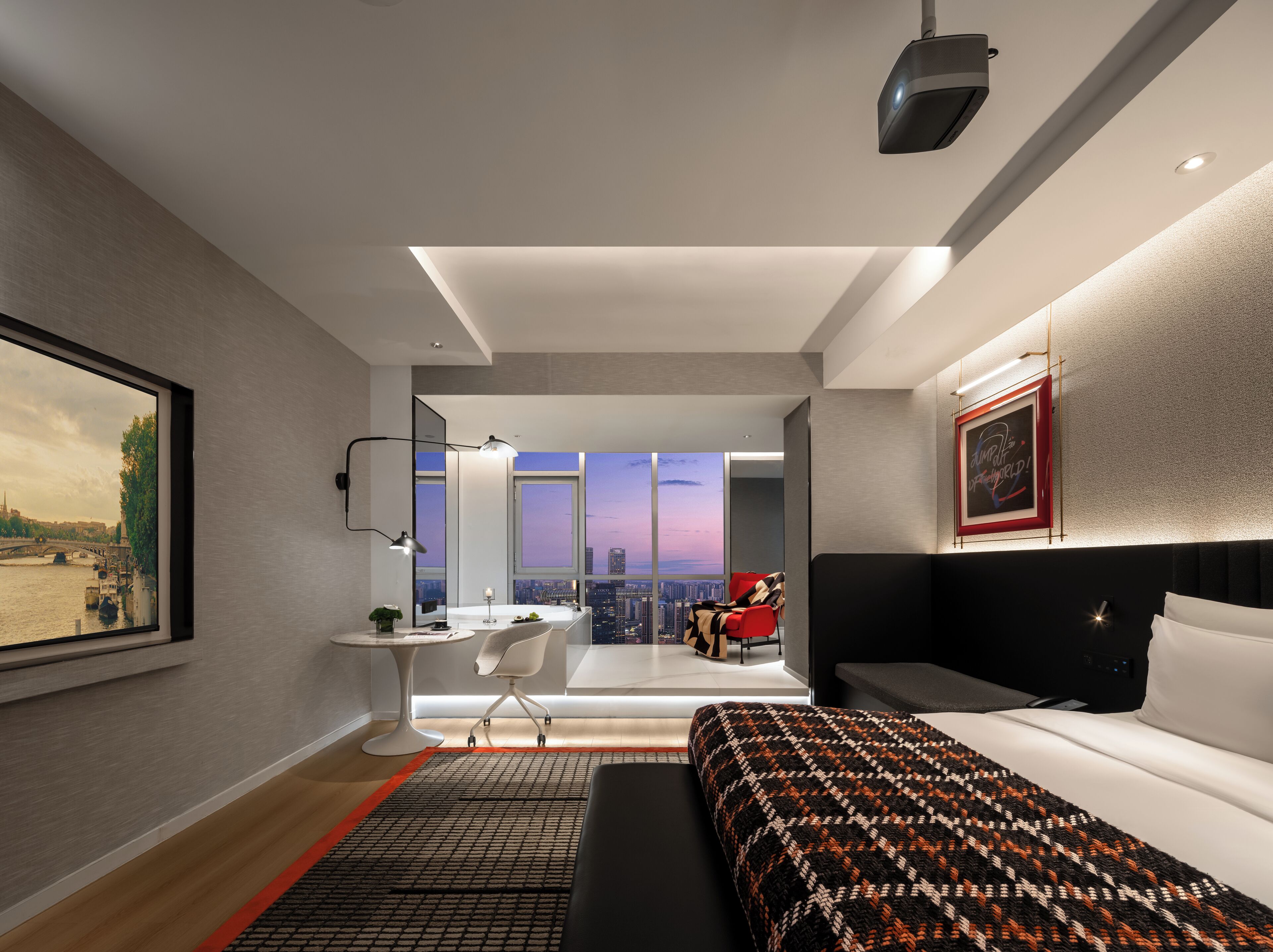Une chambre d’hôtel moderne avec vue sur la ville, comprenant un lit, un bureau et une chaise.