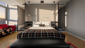 Ein modernes Hotelzimmer mit einem großen Bett, einem roten Sofa, einer Bank und Blick auf die Stadt.