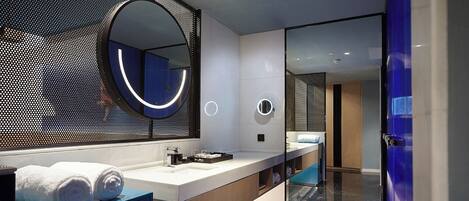 A modern bathroom with a large mirror, a sink, and a glass-enclosed shower area.