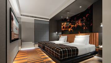 A modern hotel room with a large bed, a seating area, a wall-mounted TV, and a unique light installation.