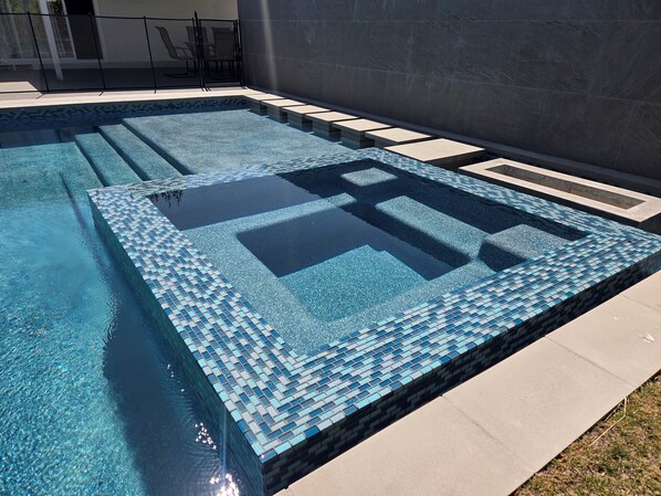 Une piscine rectangulaire dotée d’une plage carrelée et d’un motif géométrique sur le fond.