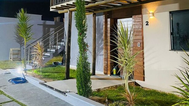 Una casa moderna de dos pisos con un balcón, un espacio exterior cubierto y un césped bien cuidado.