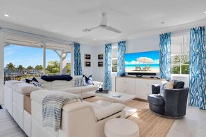 Ein modernes Wohnzimmer mit Sofa, Sessel, Couchtisch und einem Flachbildfernseher.