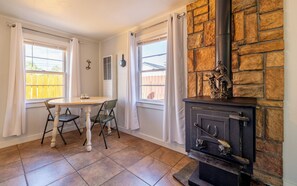 Um quarto aconchegante com lareira, uma mesa de jantar com cadeiras e janelas amplas com cortinas.