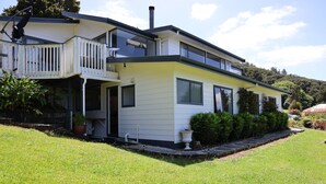 A two-story house with a balcony, a front porch, and a well-maintained lawn. - Safe Haven Hillside Retreat (Maungatapere)