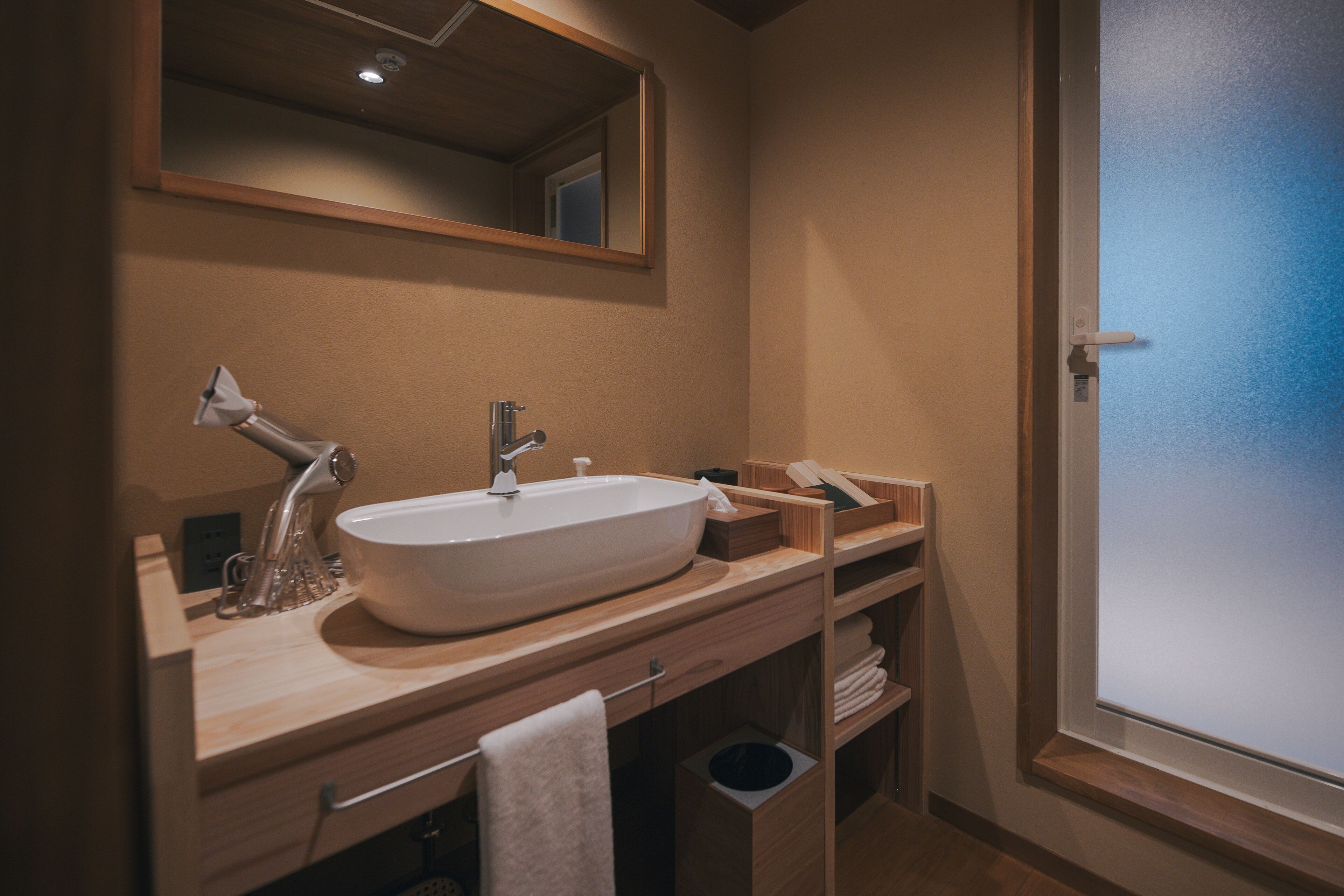 A modern bathroom with a large vessel sink, a mirror above it, and wooden cabinetry.
