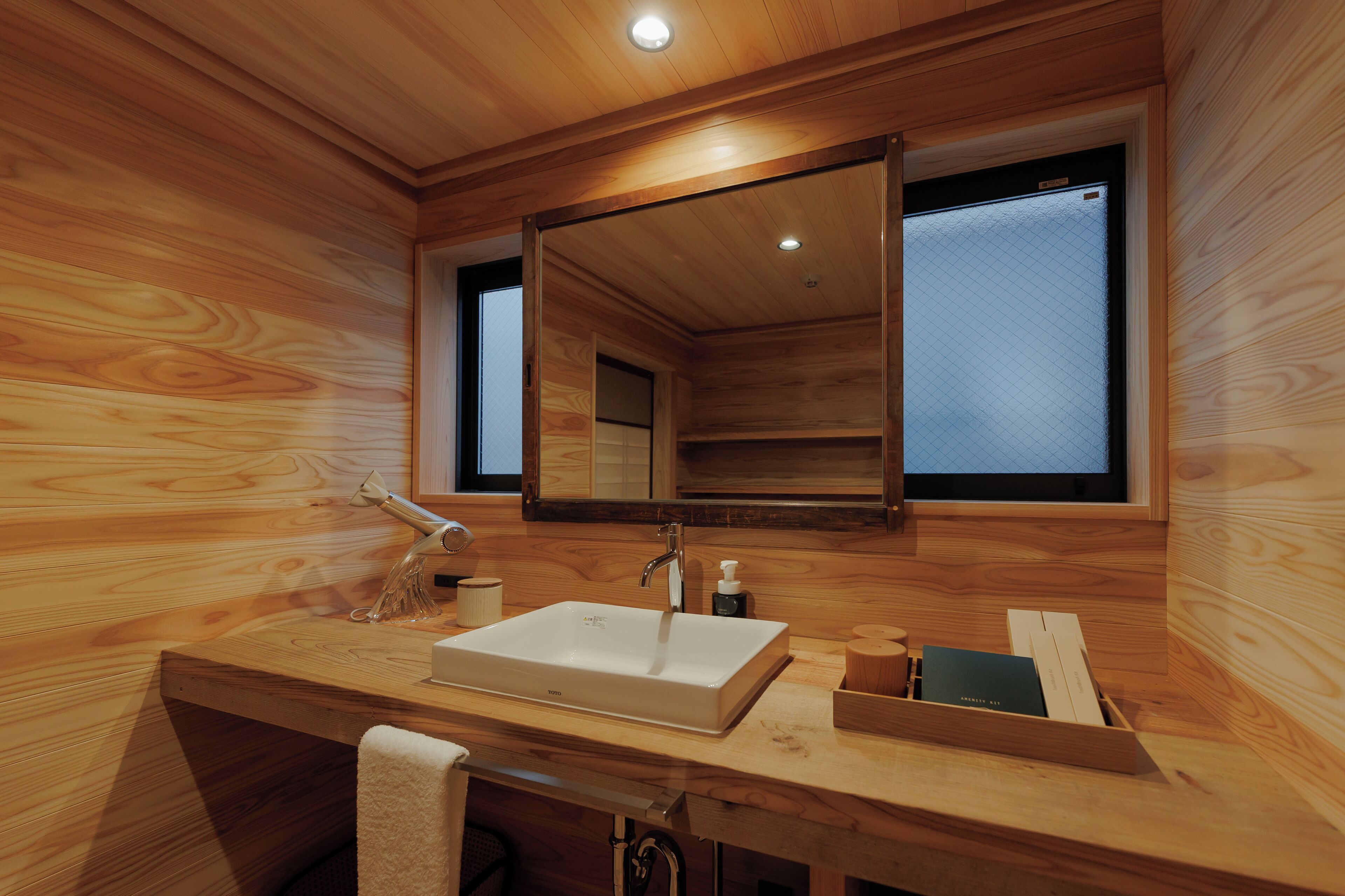Baño de cabaña de madera con un espejo grande, un lavamanos y una ventana.