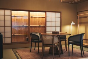 Perinteinen japanilainen huone, jossa on tatamimatto, matala pöytÀ ja neljÀ tuolia.
