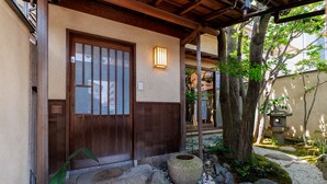 A traditional Japanese entrance with a wooden door, stone steps, and a stone lantern. - NIPPONIA Niigata Furumachi Kagai (Niigata)