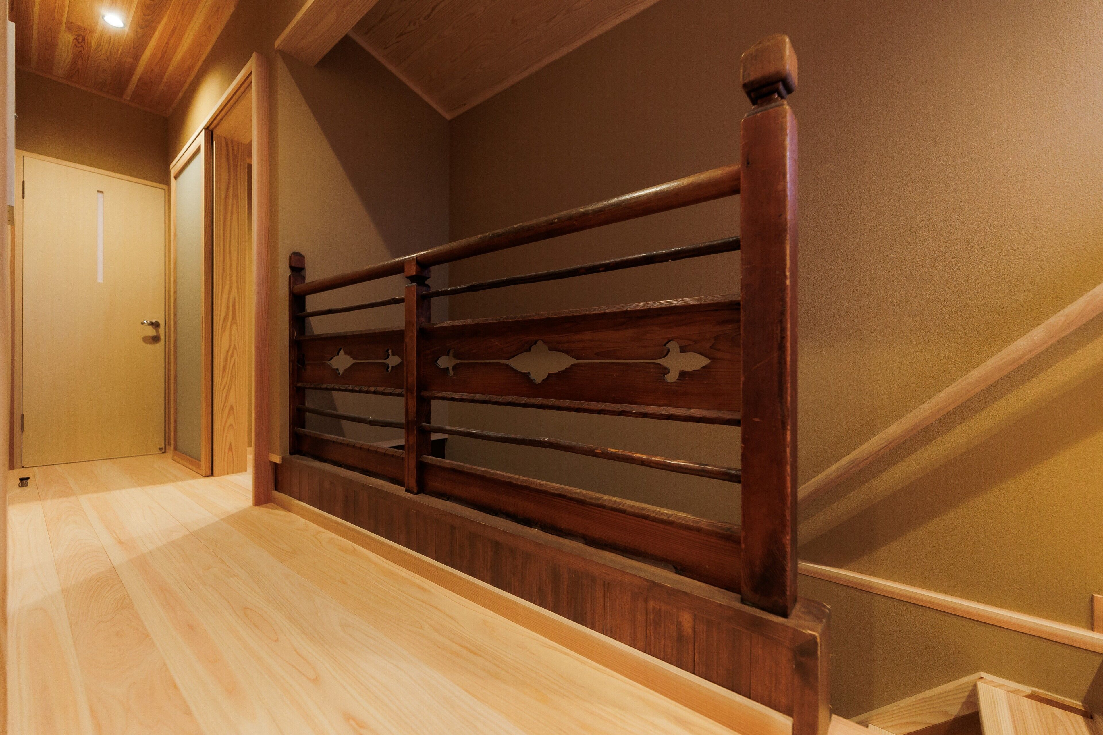 Un escalier en bois avec une rampe, un plancher en bois et une porte en haut.