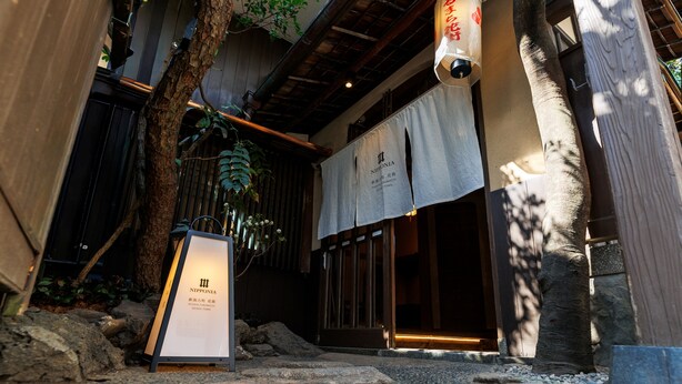 A traditional Japanese building with a wooden exterior, a stone pathway, and a signboard. - NIPPONIA Niigata Furumachi Kagai (Niigata)