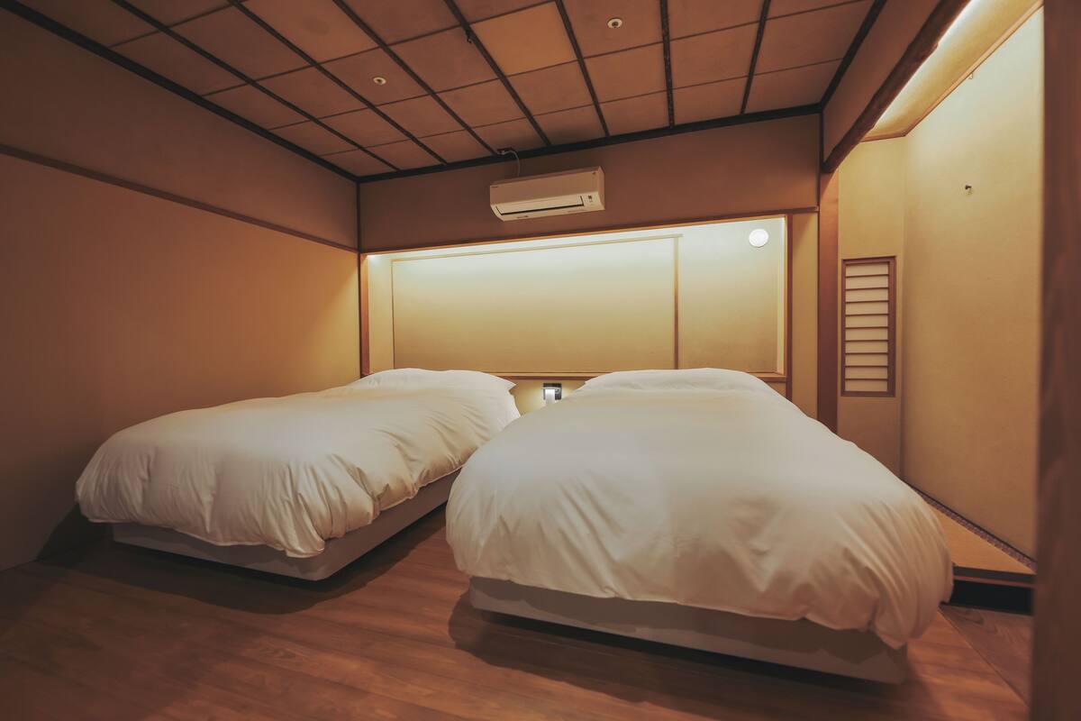 Ein Zimmer mit zwei Betten, einer Deckenklimaanlage und einer Wandleuchte.